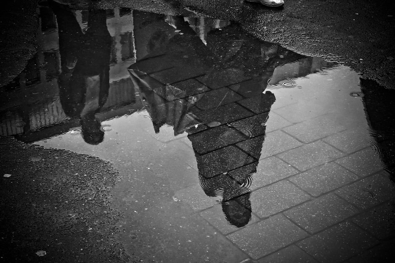 A puddle on the lane, holding the whole sky.